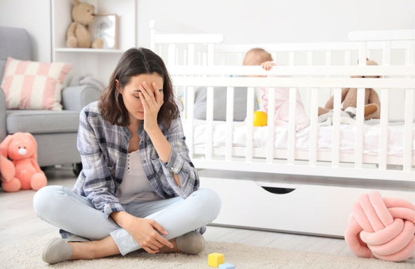 想像以上に大変な産後。今こそ必要な『ママのケア』とは？ベビーベッドの前で疲れてうなだれるママ